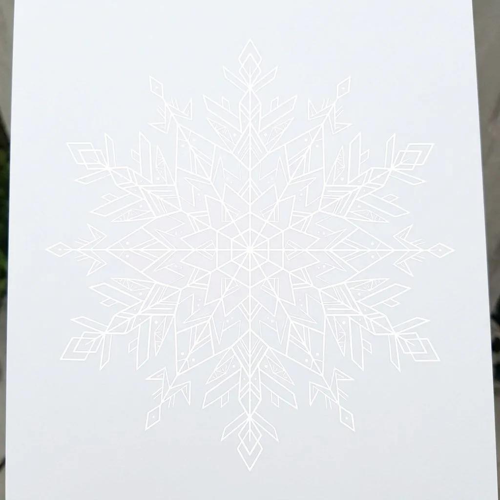 Dessin de tatouage d'un flocon de neige géométrique blanc aux lignes fines sur fond clair.