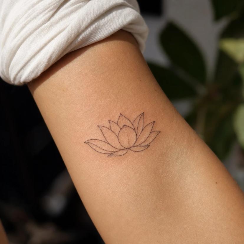 Tatouage lotus fine-line au trait fin sur le bras d'une femme