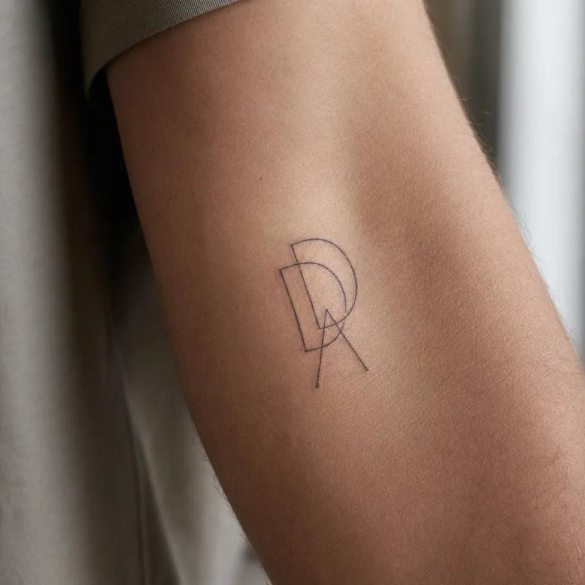 Initiales fine-line à l'avant-bras, exemple idéal de premier tatouage discret